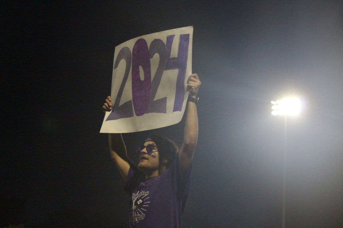 A senior cheerleader holding up a class of 2024 sign. 