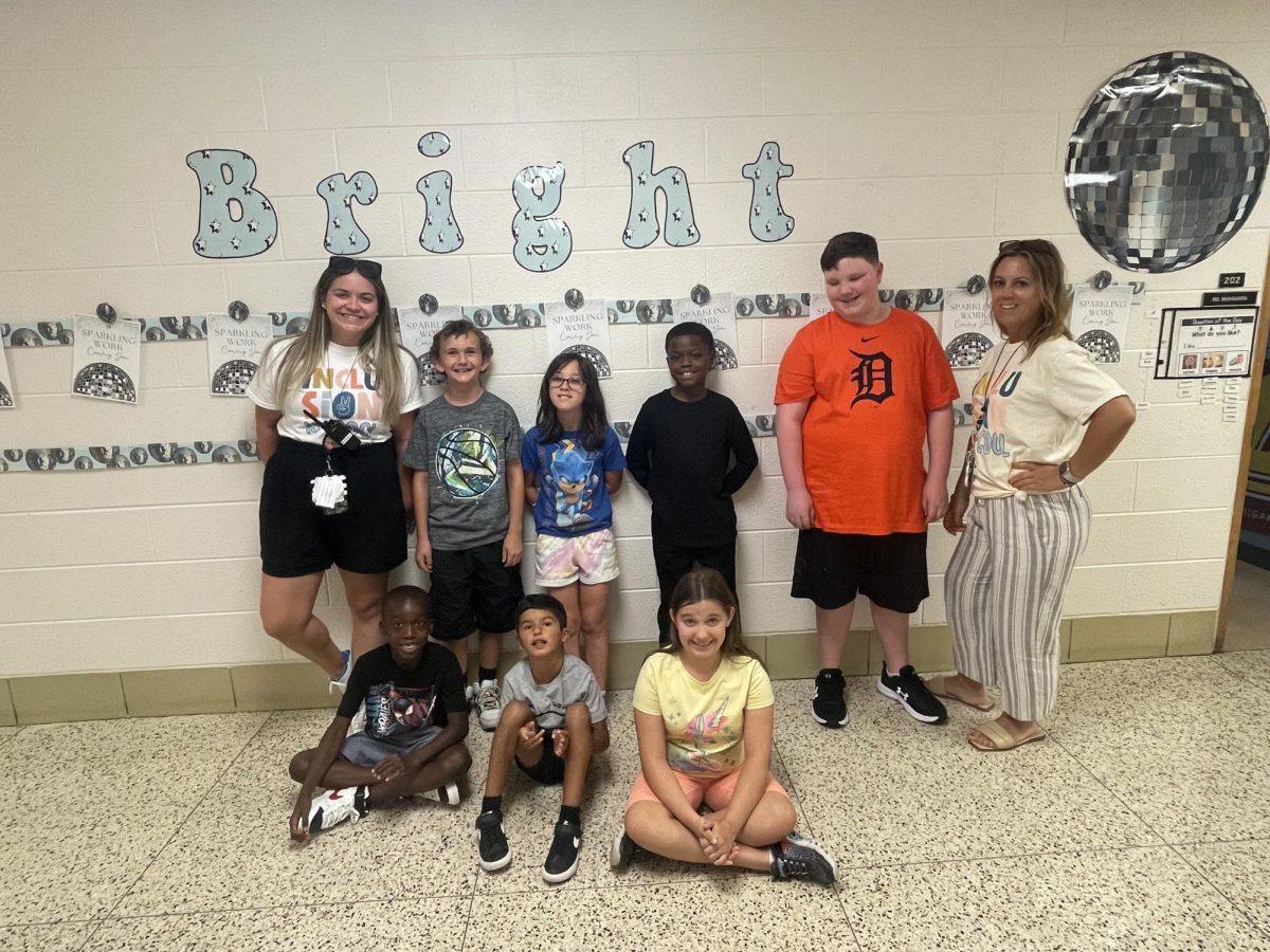 Pictured here is Ms. McNamara (left) with her students in front of their classroom.